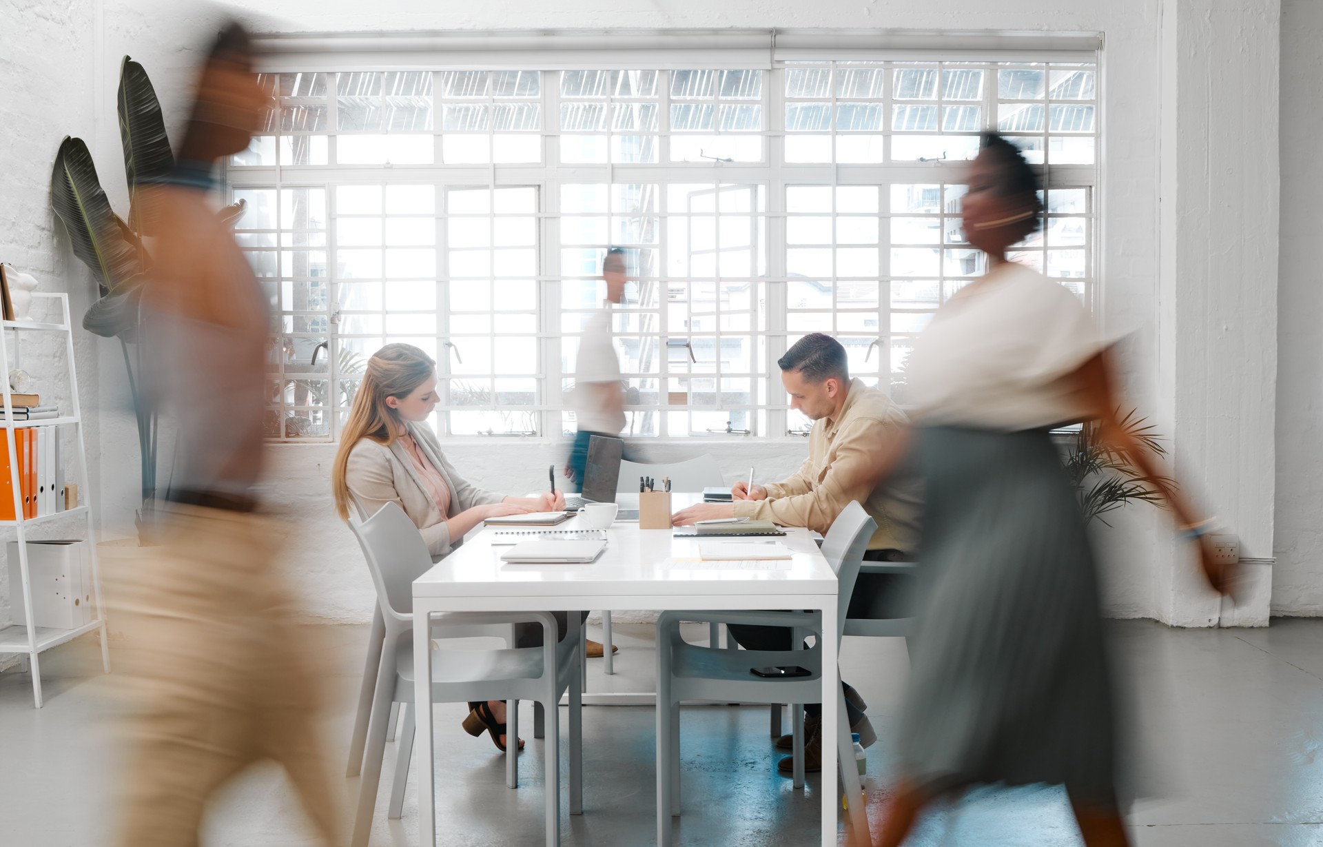 Blurred designers, marketing or freelance professionals working together in a modern office. Business men and women busy, walking and active in a creative workplace, workstation or environment