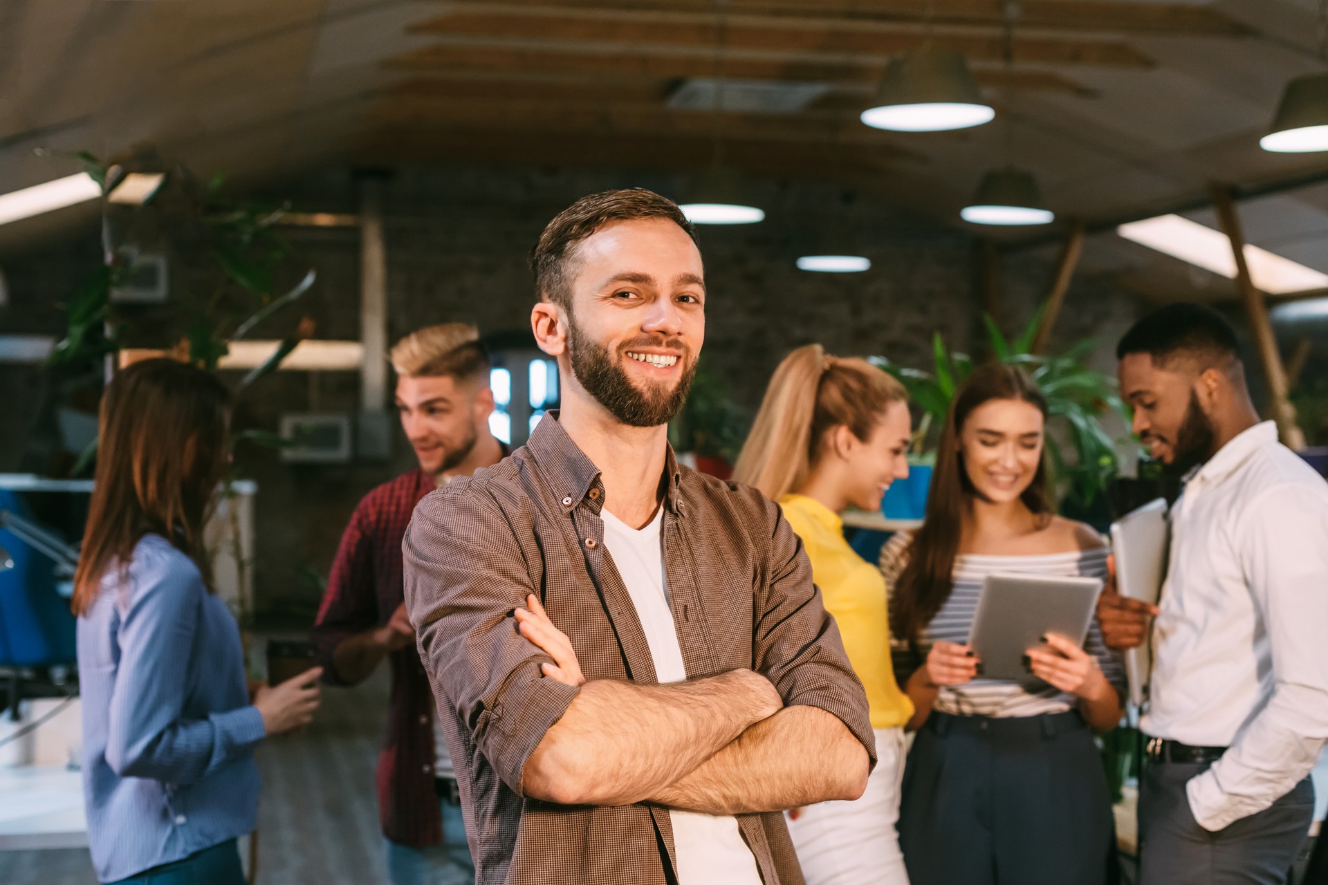 Smm manager smiling to camera, standing in busy creative office